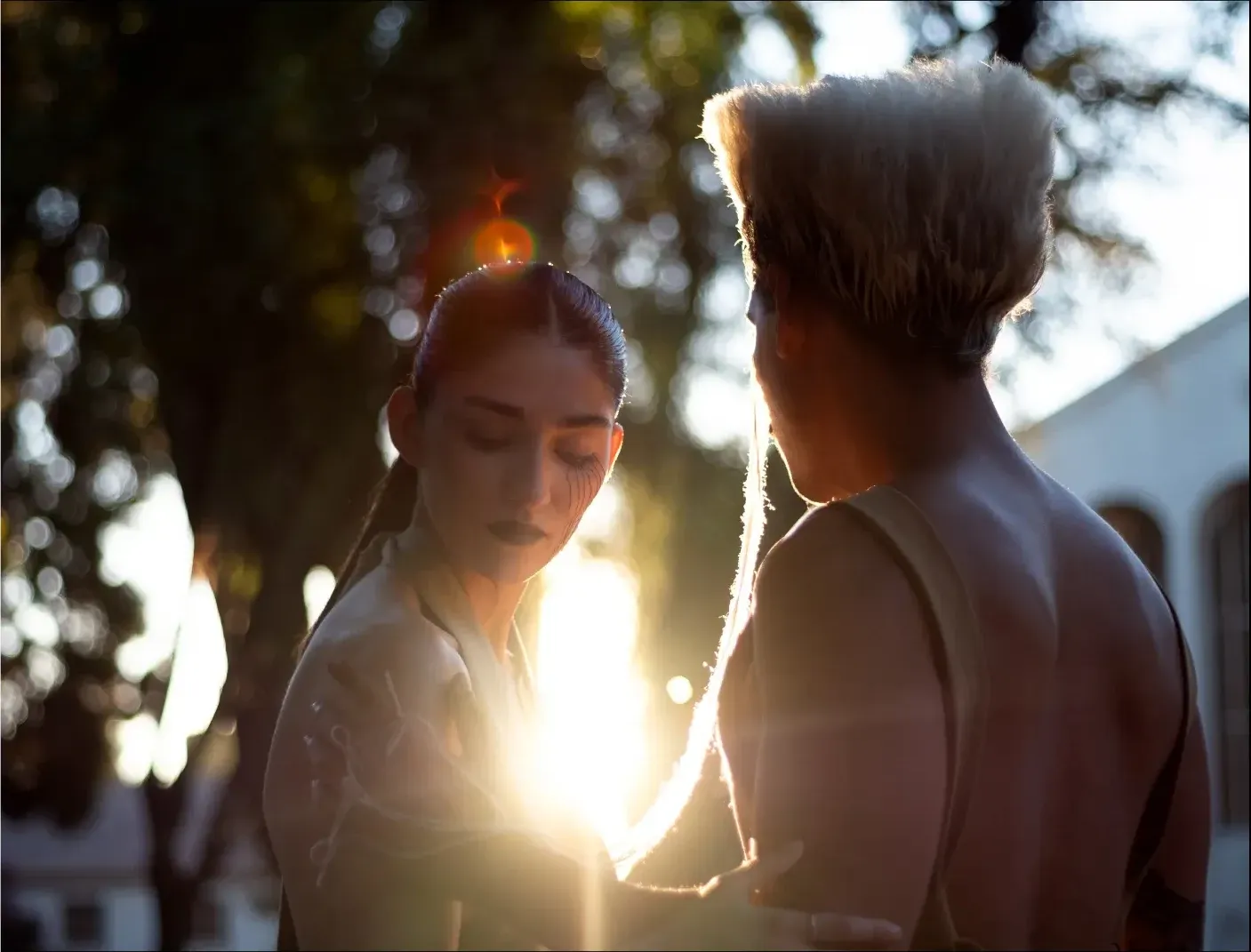 Pareja frente a frente con el sol del atardecer entre ellos
