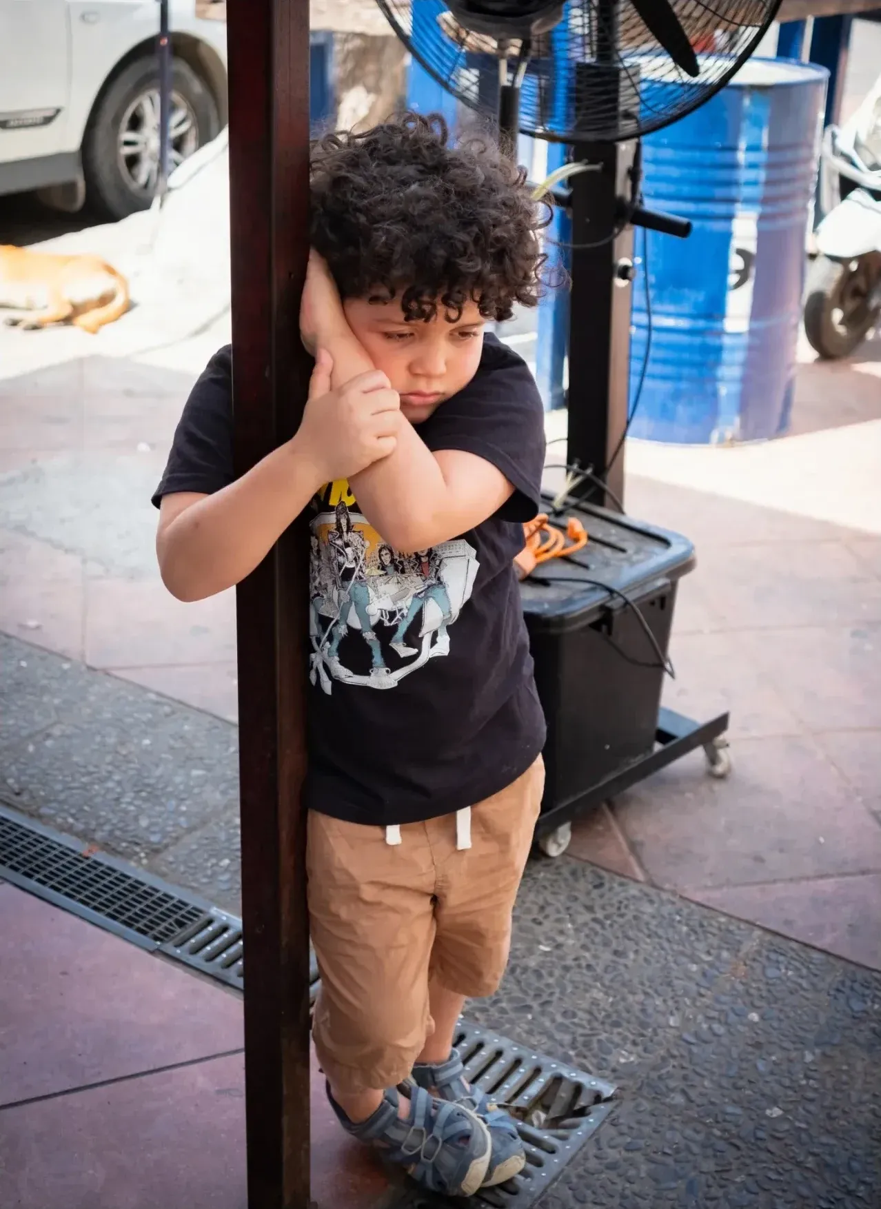 Niño apoyado en un poste con expresión aburrida